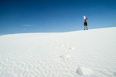 Man standing on sand dune against clear sky