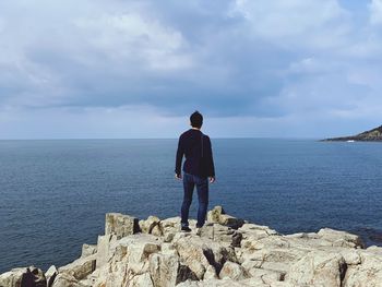 Rear view of man looking at sea against sky