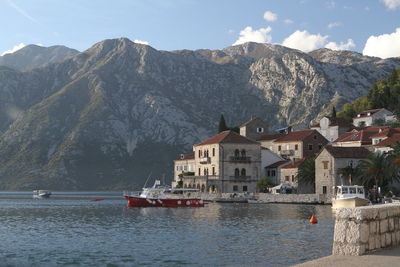 Sailboats in sea by buildings against sky