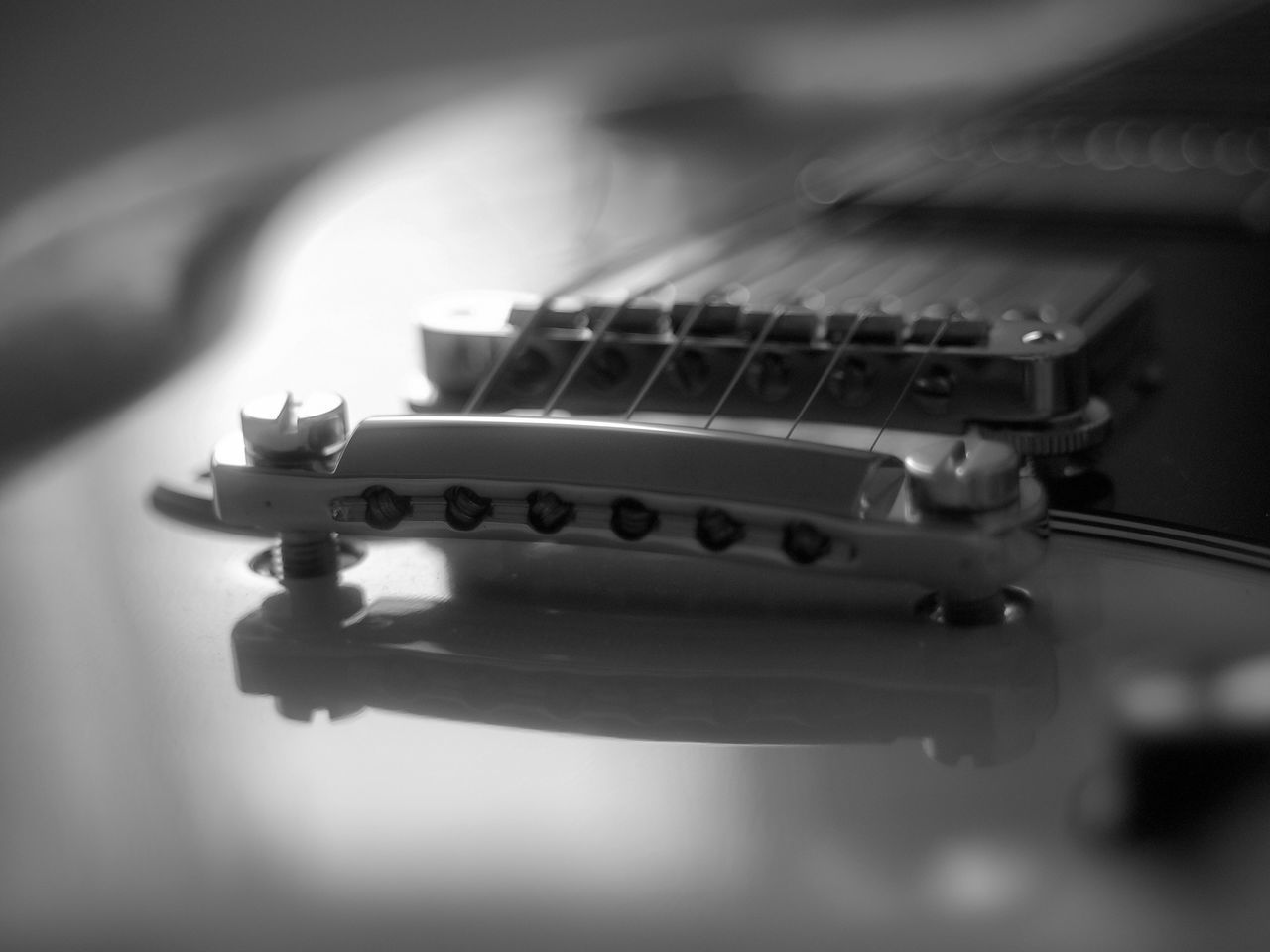 CLOSE-UP OF GUITAR ON TABLE AGAINST BLACK BACKGROUND