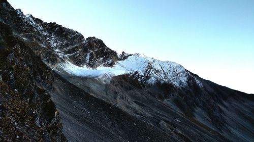 Close-up of snow capped mountain against clear sky