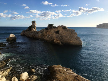 Rocks on sea shore against sky