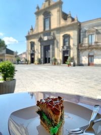 Close-up of food on table against building in city