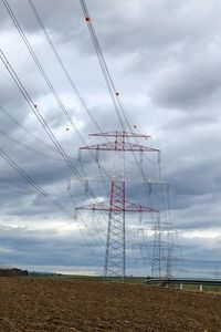 Low angle view of electricity pylon on field against sky