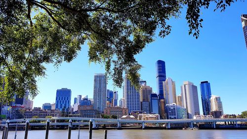City by river and buildings against clear sky