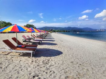 Lounge chairs at beach against sky