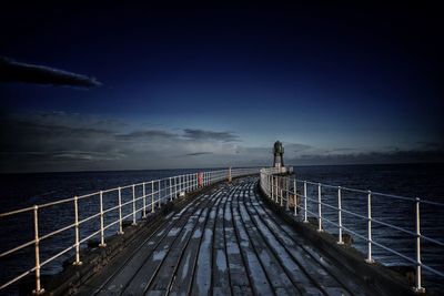 Pier over sea against blue sky