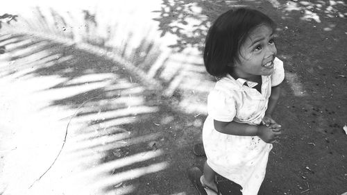 High angle view of curious girl standing on street during sunny day