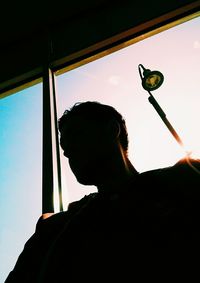 Low angle view of silhouette man looking through window