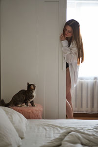Young woman with cat on bed at home