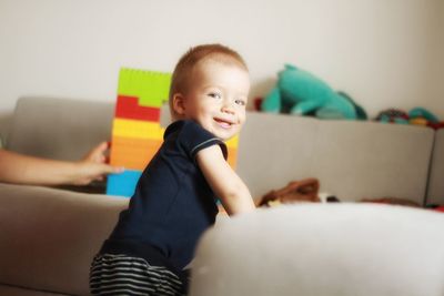 Portrait of smiling boy sitting on sofa at home