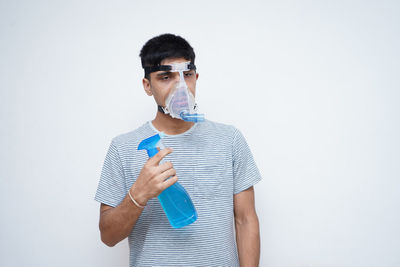 Portrait of young man drinking against white background