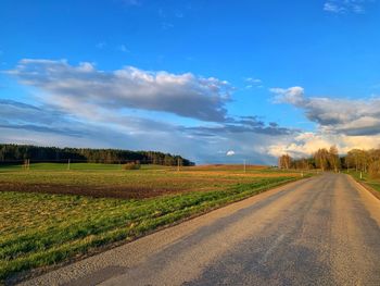 Surface level of road amidst field against sky