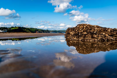 Close-up of reflection of clouds in shoreline against blue sky