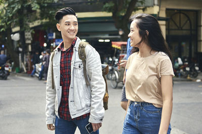 Full length of smiling young woman standing in city