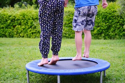 Low section of children playing on trampoline at lawn