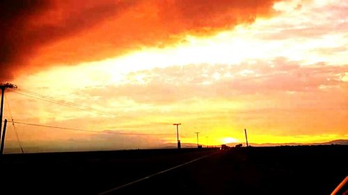 Scenic view of road against cloudy sky at sunset