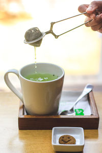 Hand pouring tea cup on table