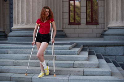 Full length of woman looking away while sitting on staircase