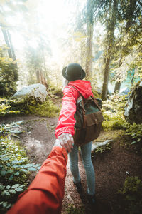 Woman holding hands of man while walking in forest