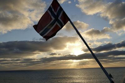 Low angle view of flag against sky during sunset