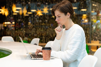 Young businesswoman looking at laptop at table