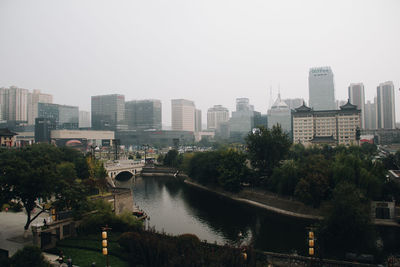 River amidst buildings in city against clear sky