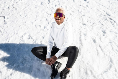 A young african american woman wearing sunglasses having fun in the snow on a winter day