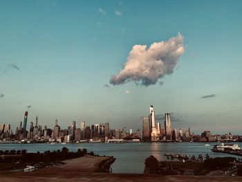 Sea by modern buildings against sky in city