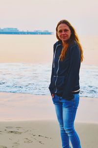 Portrait of smiling young woman standing on beach during sunset