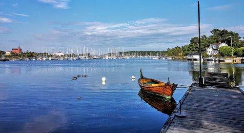 Sailboats moored in sea against sky