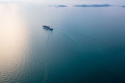 Small containers ship corgo logistic transportation sailing top speed at green sea 