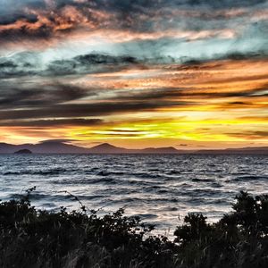 Scenic view of sea against dramatic sky during sunset