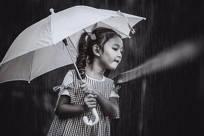 Girl looking away while standing in rain during rainy season