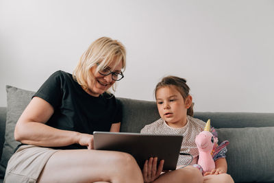 Smiling grandmother sharing digital tablet with girl at home