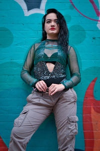 Portrait of young woman standing against wall