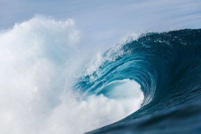 Powerful foamy sea waves rolling and splashing over water surface against cloudy blue sky