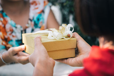 Close-up of woman giving gift box to friend