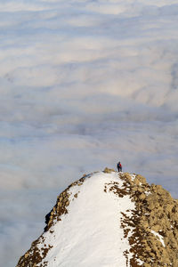 Rear view of man standing on rock against cloudy sky