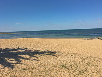 Scenic view of beach against clear blue sky