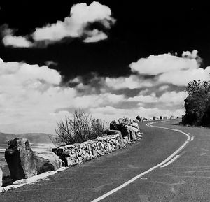 Road by trees against sky