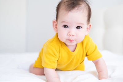 Portrait of cute baby boy lying on bed at home