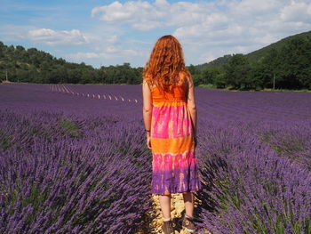 Rear view of woman standing on field during rainy season