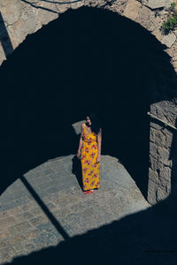 Rear view of woman with umbrella standing against built structure