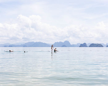 People in sea against sky