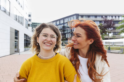 Happy redhead woman with daughter standing at hafencity