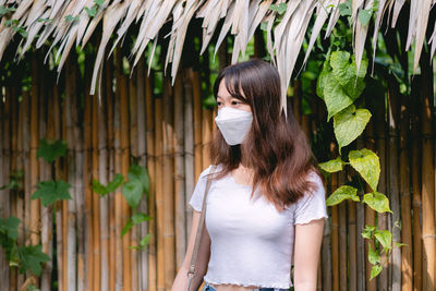 Young woman standing against palm tree