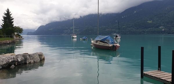 Sailboats moored on lake against sky