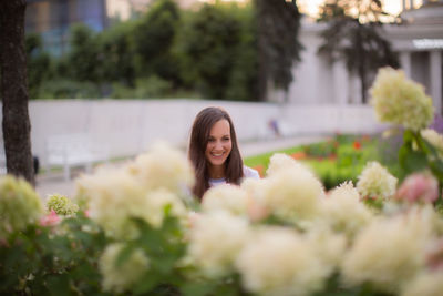 Portrait of smiling young woman by flowering plants