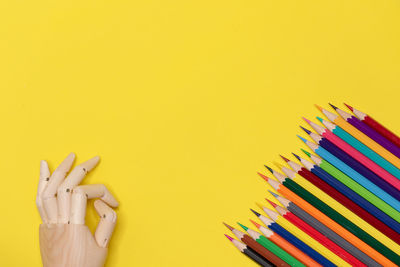 Close-up of multi colored pencils against yellow background